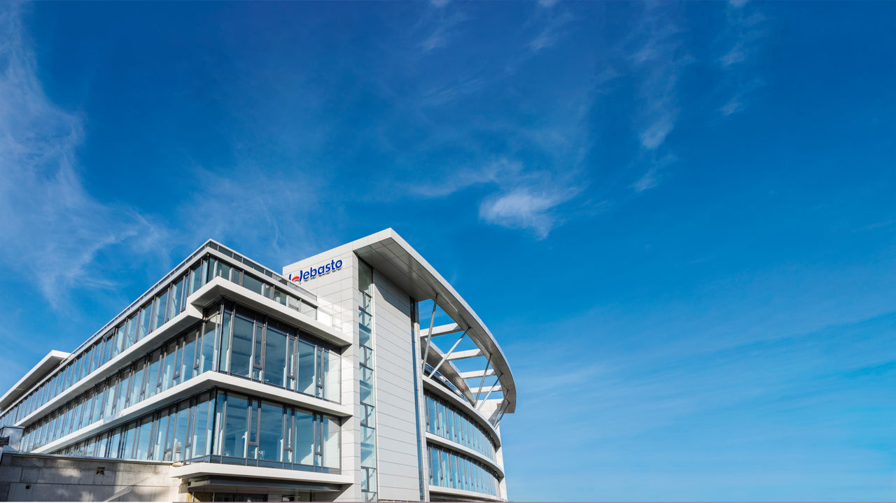 Webasto corporate headquarters façade under blue sky, highlighting Webasto as a global systems partner for roof systems and vehicle electrification.