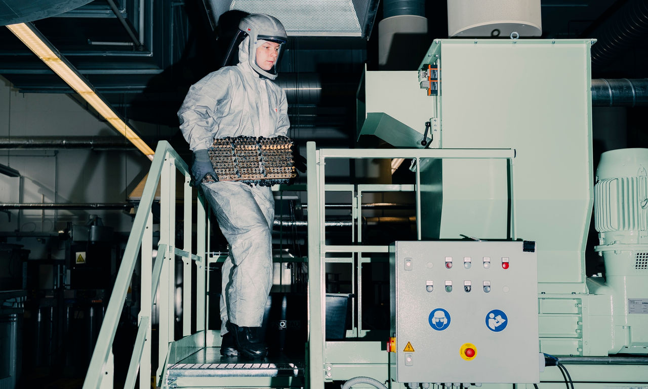 Mitarbeiter in Schutzanzug transportiert Batterie‑modul zur Recyclinganlage; Visual für Pressemitteilung über Webastos Ansatz zur nachhaltigen Batterieverwertung